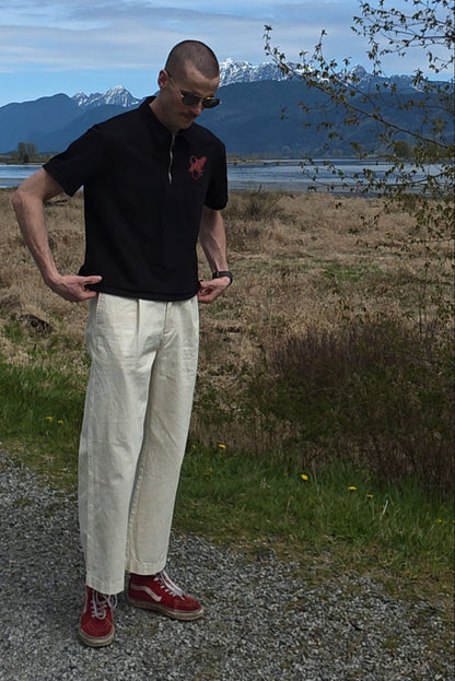 Person standing on a gravel path with a scenic background of mountains and trees.