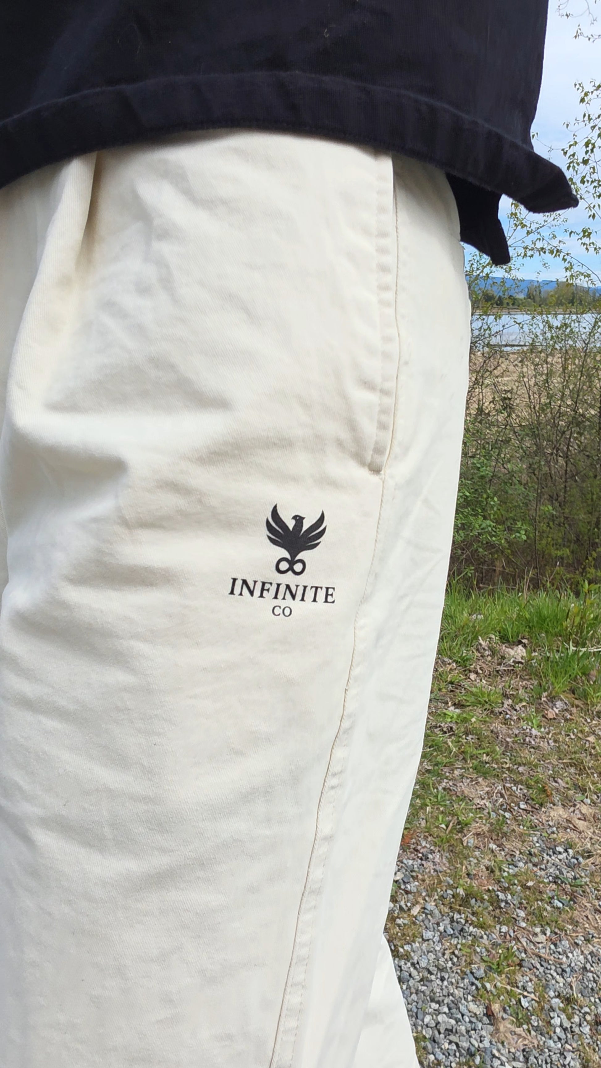 White pants with 'Infinite Co' logo worn by a person outdoors.