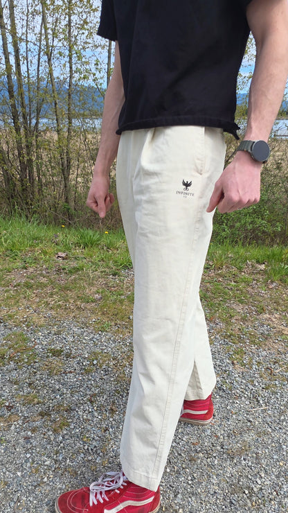 Person wearing white pants with a Infinite Co logo outdoors.