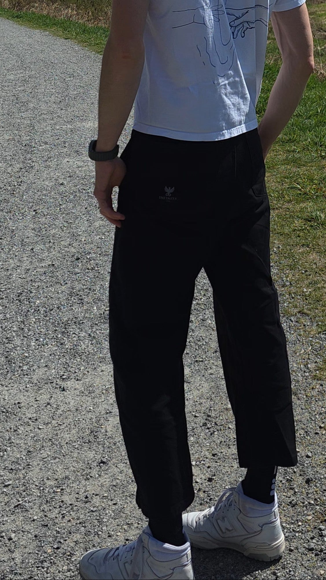 Man walking on a path wearing Infinite Co FUNDAMENTAL Barrel Leg Chinos with trees and open sky in the background