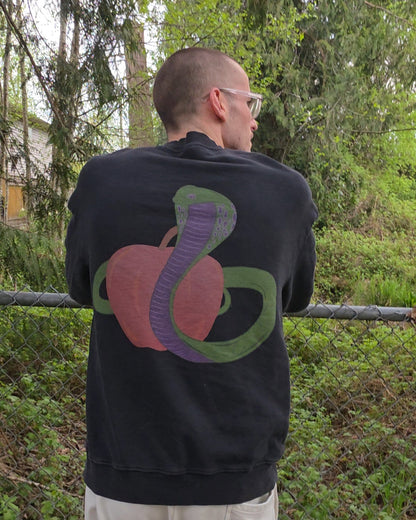 Person wearing a black EDEN Oversized Crewneck with colorful design outdoors