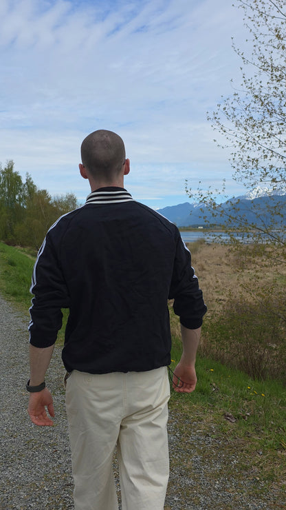 Man walking on a path with a scenic background of mountains and water.
